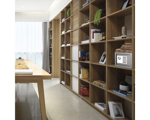 Raft din lemn cu cărți, obiecte decorative și un seif într-o cameră luminoasă