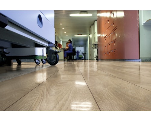 Podea de lemn deschisă la culoare într-un coridor de spital cu echipamente medicale și personal