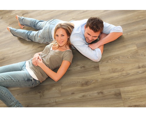 Un cuplu stă întins pe o podea laminată din lemn de culoare deschisă.