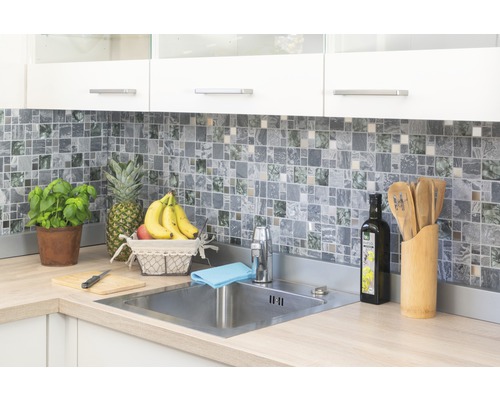 Bucătărie luminoasă cu gresie mozaic, chiuvetă din oțel inoxidabil și ingrediente proaspete.