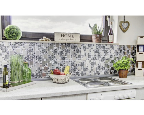 Prim-plan cu o bucătărie modernă cu plăci de mozaic ca protecție împotriva stropilor, aragaz și diverse obiecte decorative.