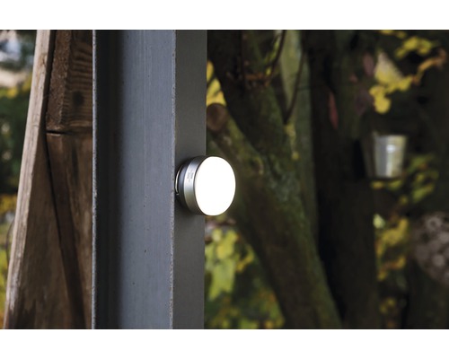 O lampă rotundă de exterior este montată pe un stâlp.