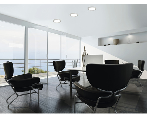 Cameră de zi luminoasă cu spoturi de tavan, fotolii și fereastră mare