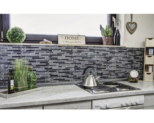 Scenă de bucătărie cu plăci de mozaic, ceainic din oțel inoxidabil și elemente decorative.