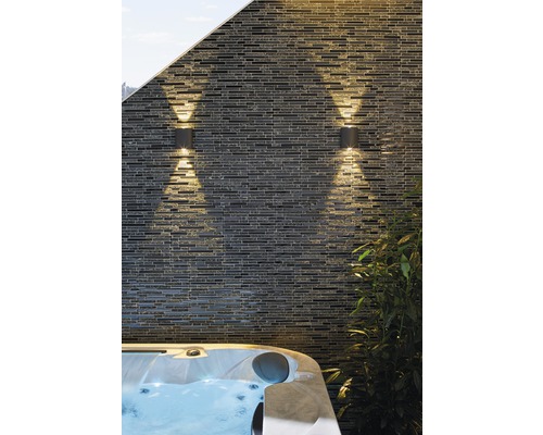 Două corpuri de iluminat exterior pe un perete de piatră lângă o cadă cu hidromasaj