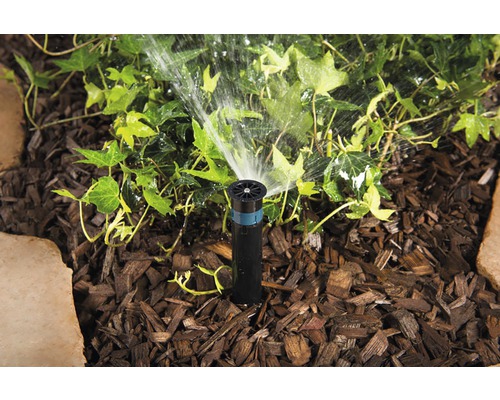 Aspersor retractabil udând plantele din grădină.