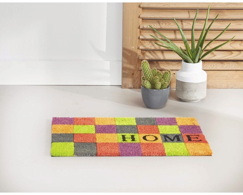 Covoraș cu model de tablă de șah și cuvântul Acasă în fața unui perete alb