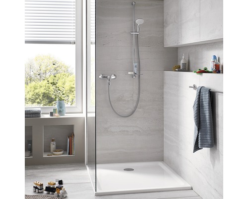 Baie modernă cu duș, robinet și cadă de duș albă.