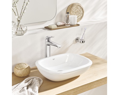 Pe o masă de lemn sunt prezentate o chiuvetă, un robinet, un prosop și un recipient.