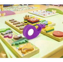Scenă cu masă de joacă și diverse puzzle-uri din lemn și o lampă balenă violetă.