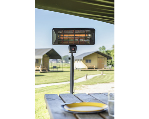Încălzitor de terasă pe o masă cu vedere spre un câmp cu corturi