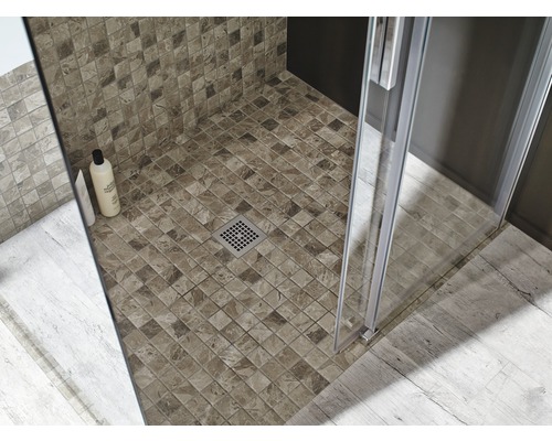 Prim-plan al unui duș cu gresie mozaic, cabină de duș și scurgere