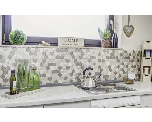 Scenă de bucătărie cu plăci de mozaic în model hexagonal, plită și decorațiuni.