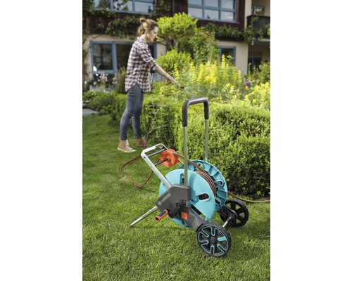 Femeie folosind căruciorul pentru furtun de grădină Gardena în grădină