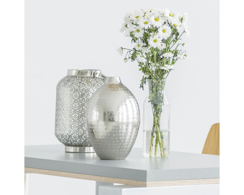 Scenă decorativă cu felinar, vază și buchet pe o masă.