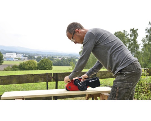 O persoană șlefuiește lemn cu o șlefuitoare cu bandă de la Einhell.