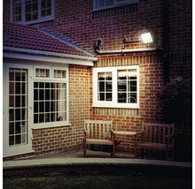 Exteriorul unei case cu fațadă din cărămidă, iluminată de un reflector LED montat pe perete