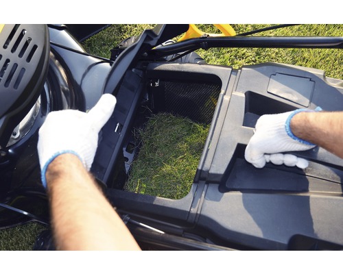 Mașină de tuns iarba cu coșul de colectare a ierbii deschis și umplut cu iarbă