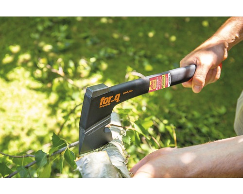 O persoană folosește un topor marca for_q pentru a tăia lemne.