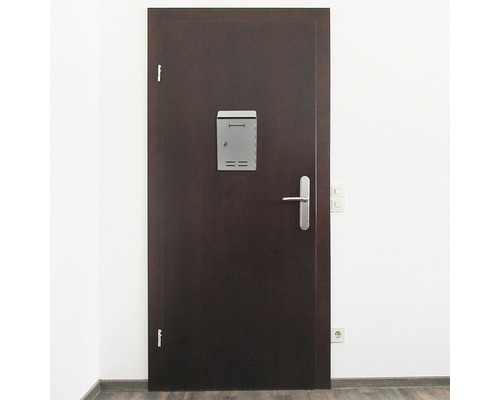 Ușă întunecată cu cutie poștală și clanță într-o cameră luminoasă.