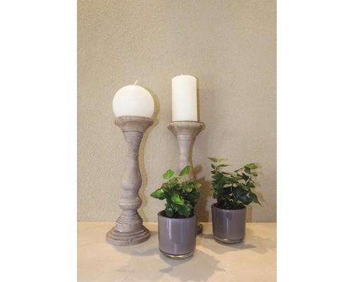 Scenă decorativă cu lumânări pe suporturi și plante de interior în ghivece