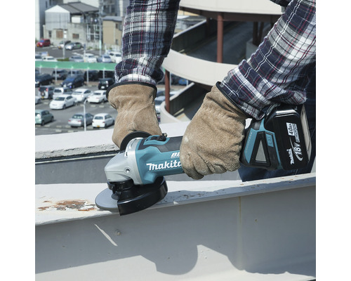 O persoană folosește un polizor unghiular fără fir Makita pentru a șlefui metal.