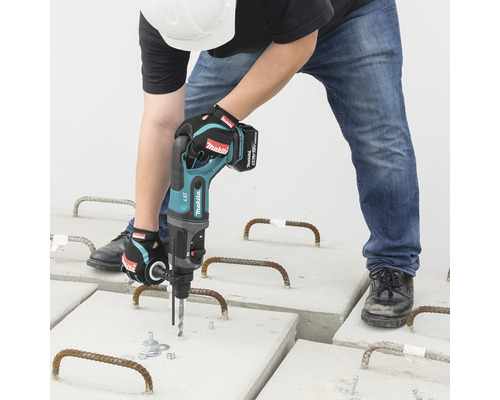 Un bărbat forează plăci de beton cu un ciocan rotopercutor cu acumulator.