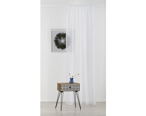 Scenă cu o draperie albă, transparentă, o măsuță cu model și o imagine înrămată pe perete