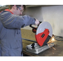 Un bărbat manevrează un ferăstrău pentru metal în timp ce taie o bucată de metal. Sar scântei.