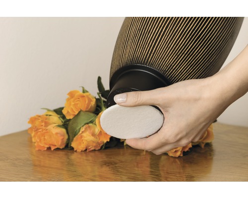 Femeie care schimbă filtrul unui purificator de aer în fața unui buchet de trandafiri