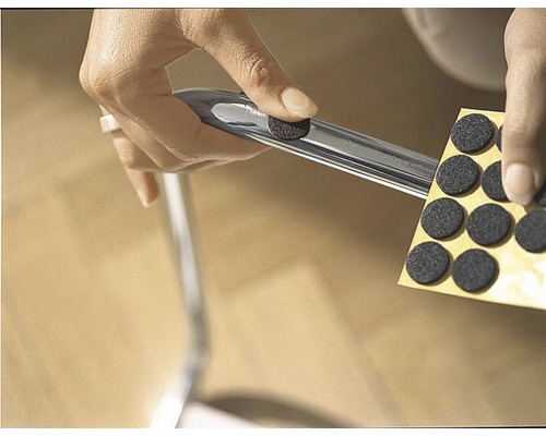 O persoană atașează un suport de pâslă la un picior de scaun pentru a proteja podeaua.