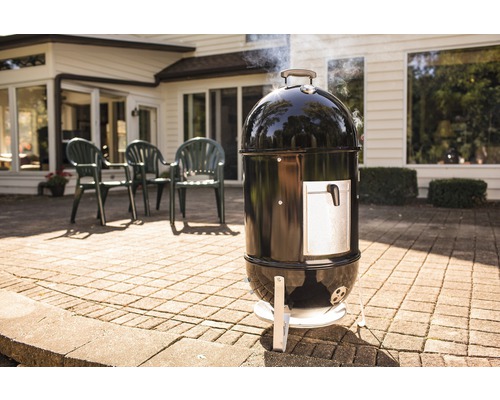 Grătar afumătoare negru cu ușă argintie pe o terasă