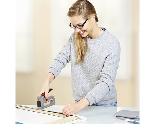 Femeie folosind un capsator manual pentru a fixa materialul pe un cadru