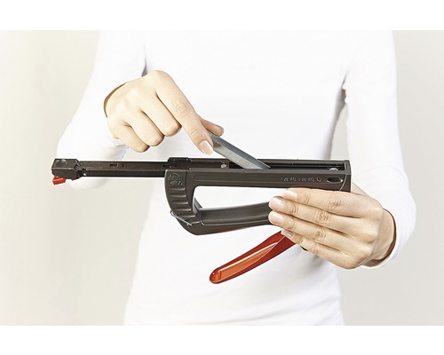 O persoană încarcă un capsator cu capse.