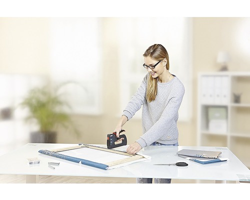 O femeie folosește un capsator pentru a întinde o pânză pe un cadru