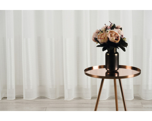 Șaluri decorative din țesătură transparentă cu dungi orizontale în fața unei mese cu aranjament floral.