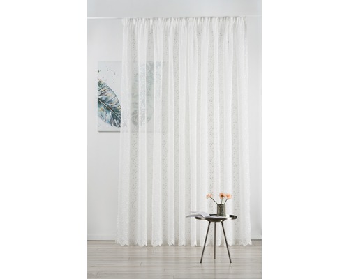 Perdea din material transparent cu model și sistem de prindere cu bandă de încrețire în fața unui perete