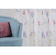 Cortină decorativă cu model de păsări lângă un fotoliu.