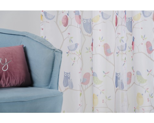 Cortină decorativă cu model de păsări lângă un fotoliu.