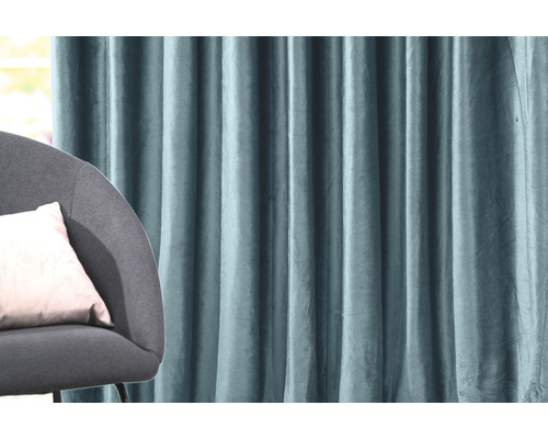 Perdea decorativă din material textil cu pliuri lângă un fotoliu cu pernă
