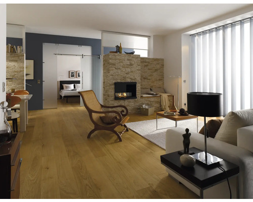 Cameră de zi luminoasă cu șemineu, podea din lemn, canapea, fotoliu și ușă glisantă spre dormitor