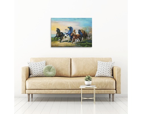 Pictură murală reprezentând cai galopând în iarbă deasupra unei canapele bej.