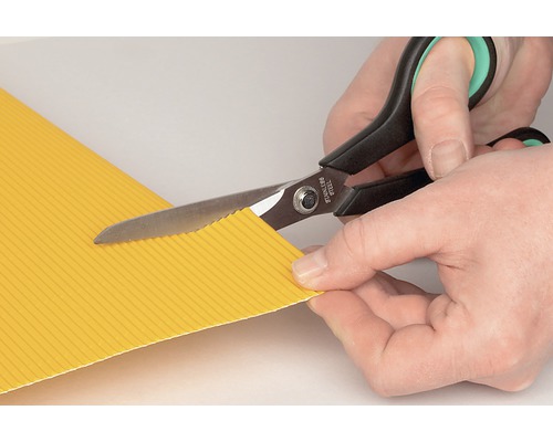 O foarfecă zimțată taie o bucată de carton ondulat galben.