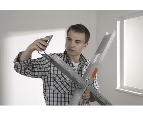 Bărbat care asamblează profile pentru gips-carton cu un unghi de fixare