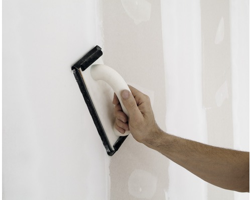 Mână șlefuind un perete cu un șlefuitor manual