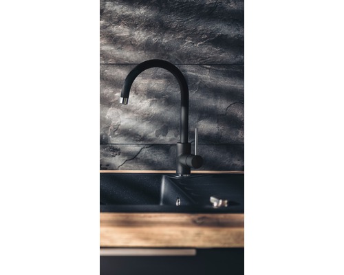 Baterie de bucătărie neagră cu chiuvetă în fața unui perete de piatră