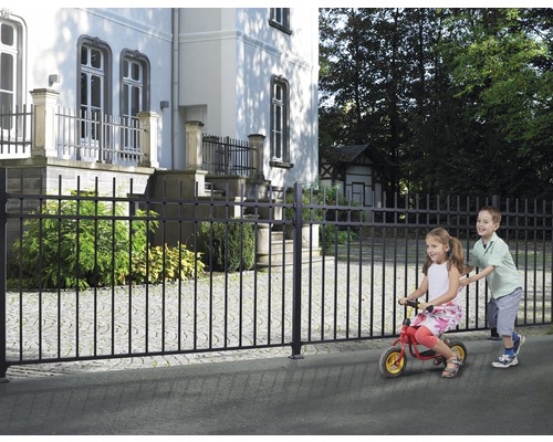 Gard metalic negru în fața unei clădiri cu copii care se joacă