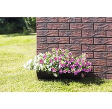 Jardinieră cu flori albe și violete în fața unui zid de cărămidă