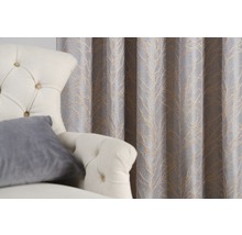 Cortină decorativă cu model de frunze lângă un fotoliu.