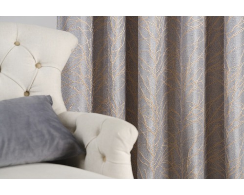 Cortină decorativă cu model de frunze lângă un fotoliu.